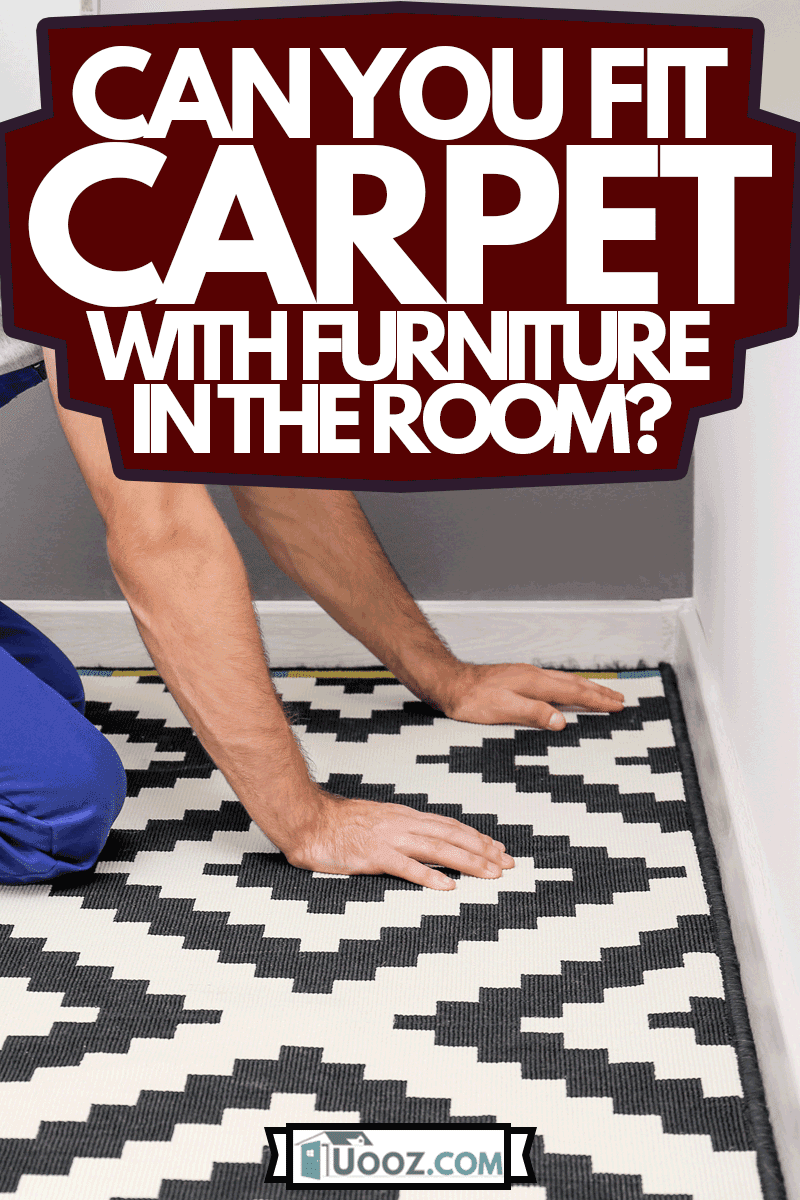 Male worker laying carpet indoors, Can You Fit Carpet With Furniture Still In The Room?