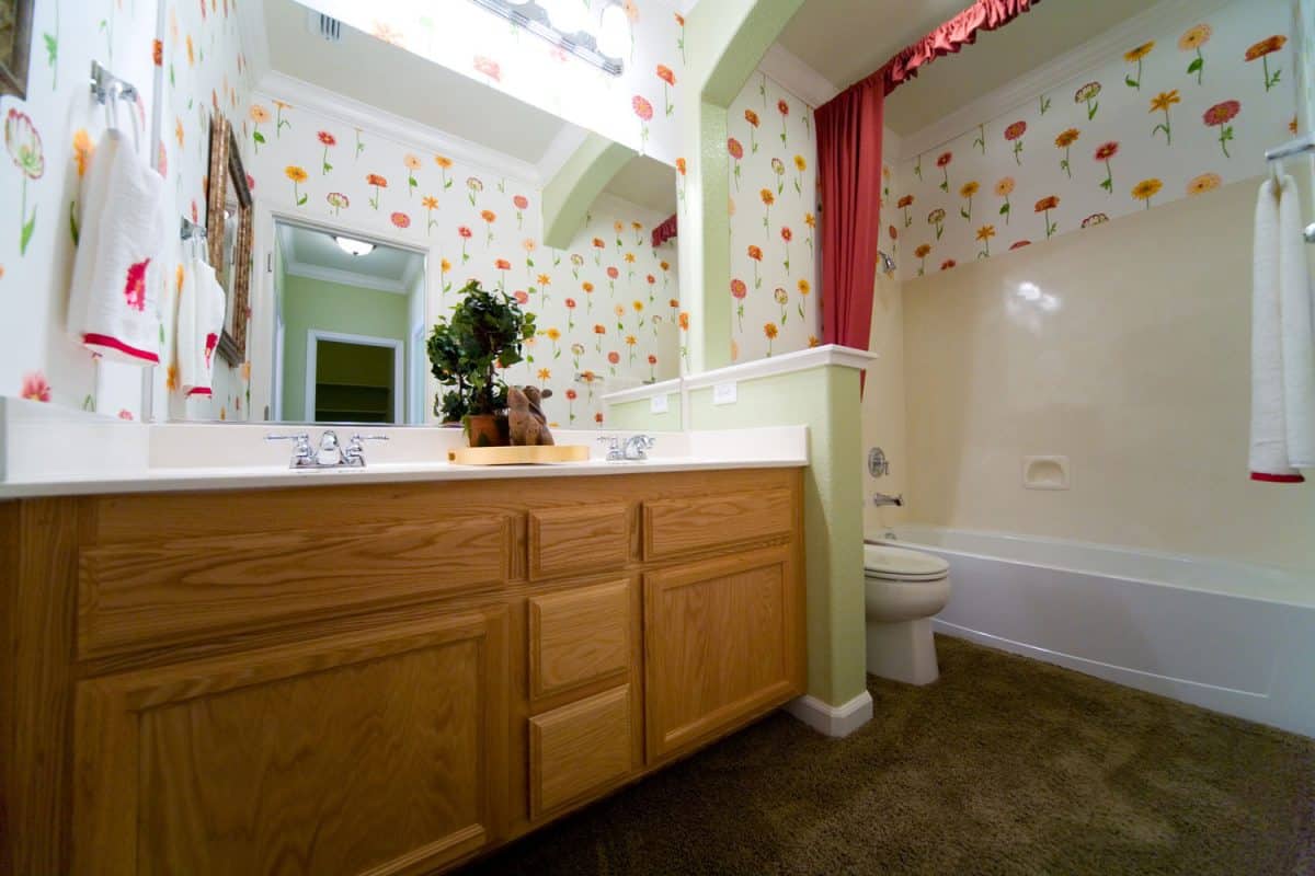 Classic designed bathroom with wooden cabinets in the vanity and flowers on the walls