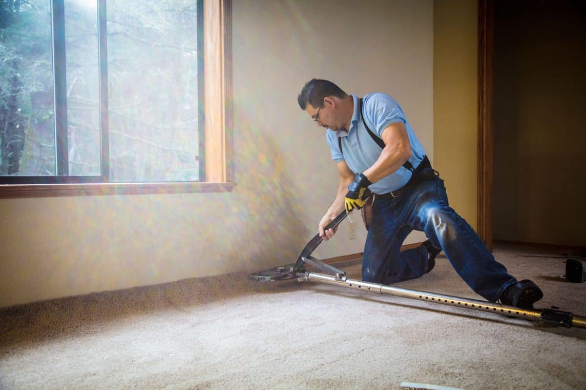 Man installing carpeting in home.