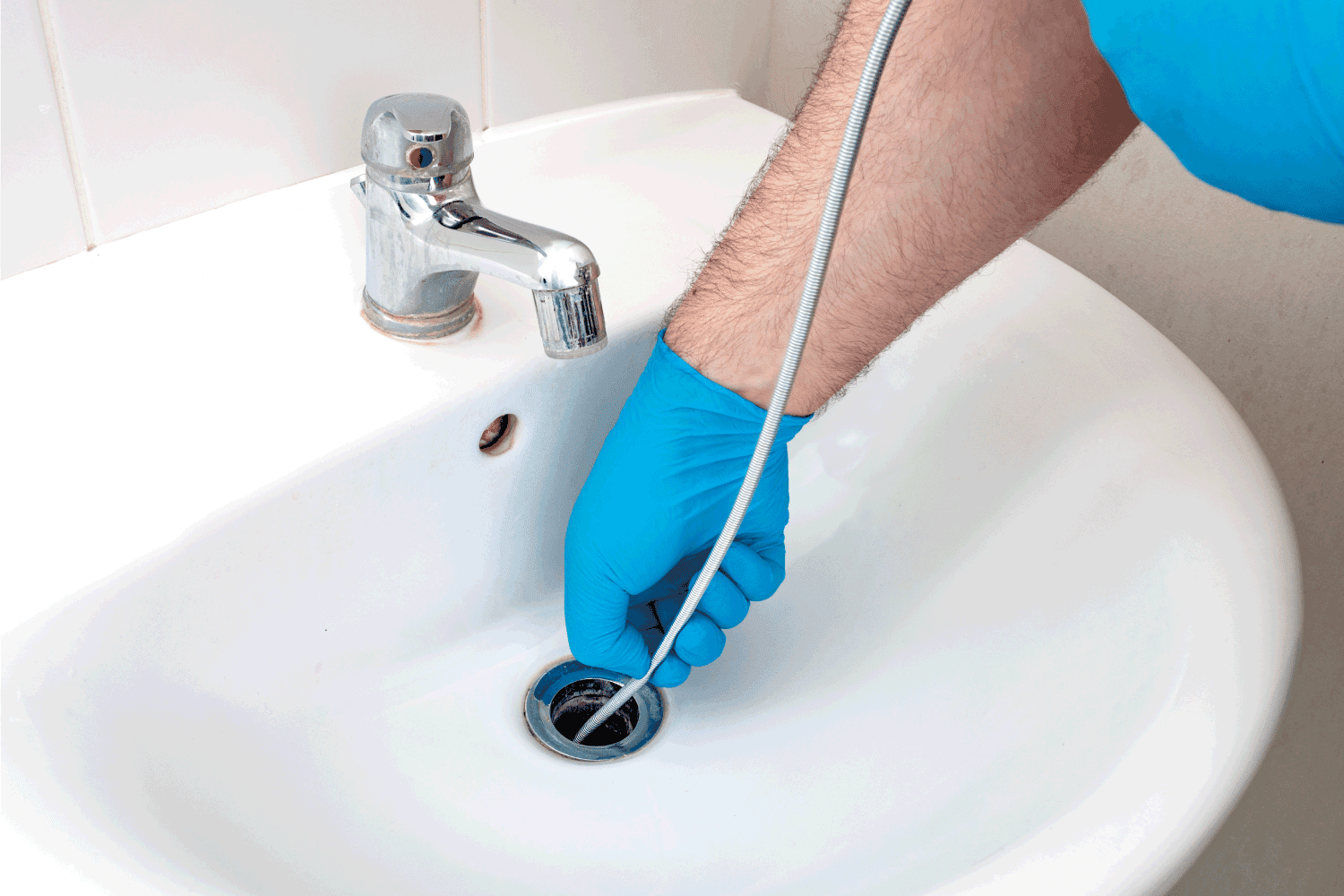 Plumbing issues, occupation in sanitation and handyman contractor concept with plumber repairing drain with plumbers snake