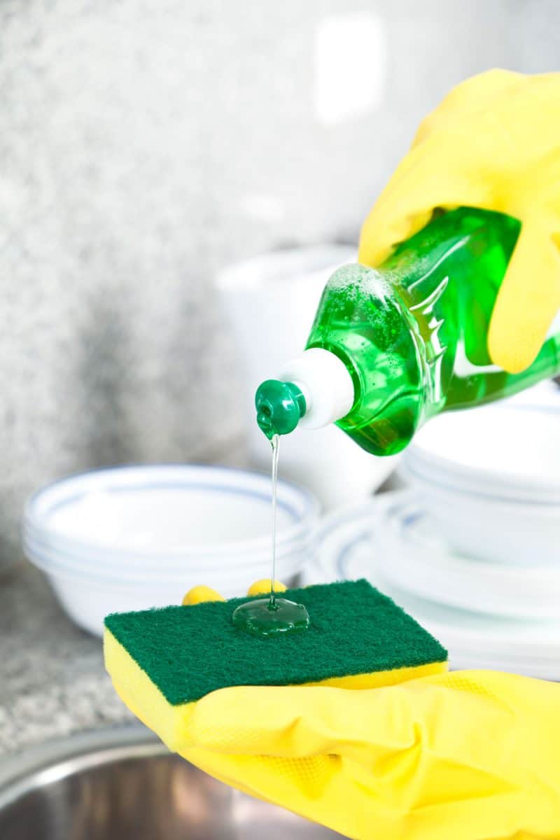 Pouring dishwashing soap on the sponge for washing the dishes