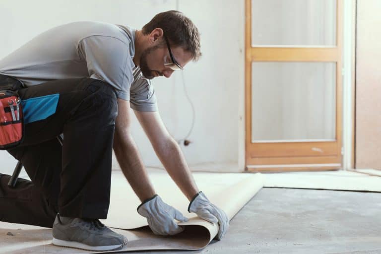 Professional contractor removing an old linoleum flooring: home renovation concept, Carpet Vs. Linoleum Cost: Which Is Cheaper?