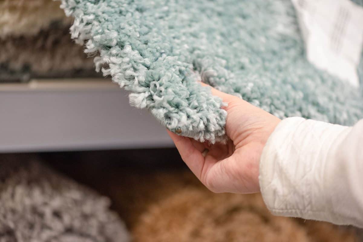 Woman holding and checking the texture of the carpet for the bathroom