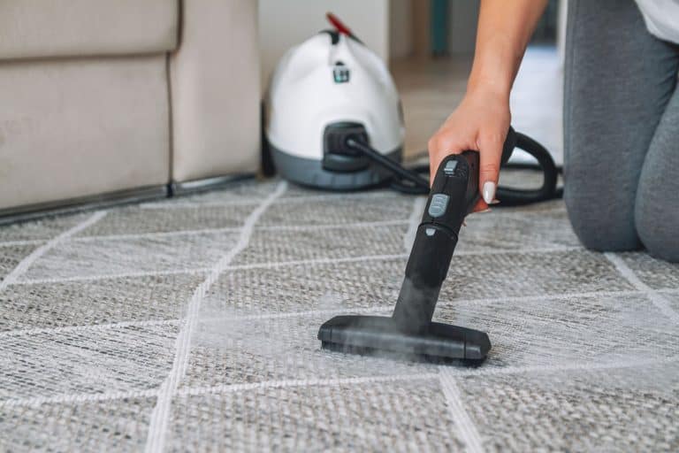 Woman using a steam vacuum cleaner in removing stains in the carpet, Can You Use A Carpet Cleaner On Your Couch?