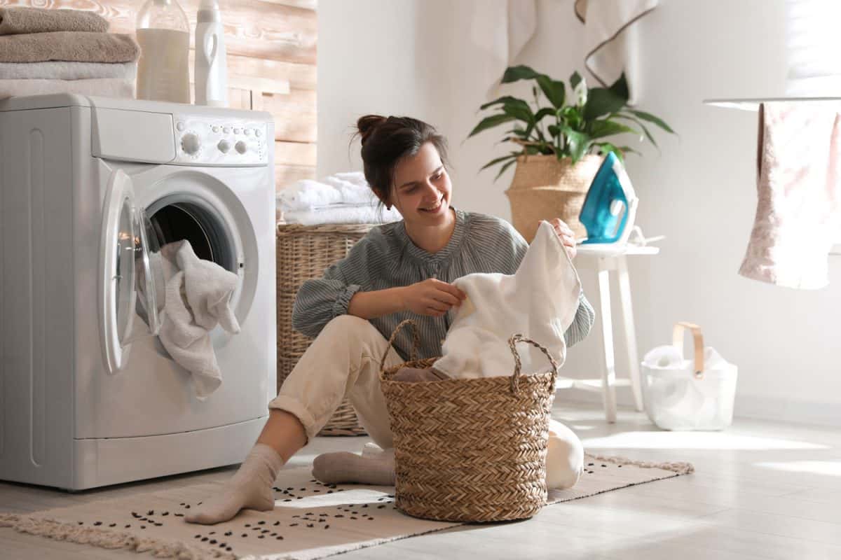 Young woman with laundry basket near dryer at home, Amana Dryer Won't Start - What To Do?