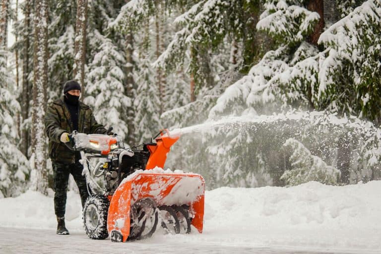 a man removes snow with a snowblower on the background of a snowy forest, Ariens Snowblower Won't Start - What To Do?