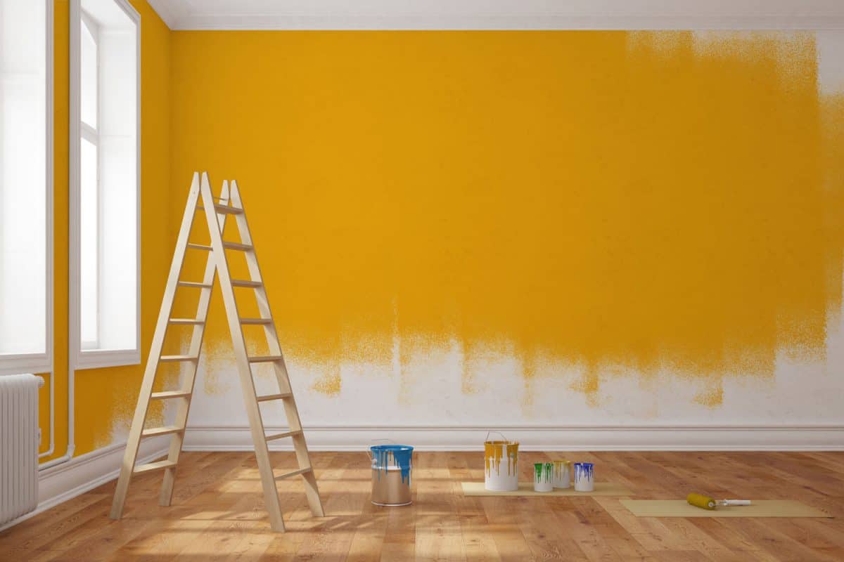 A room undergoing painting with ladders and cans of paint inside the room
