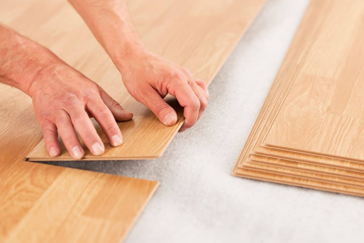 A tile setter placing a wooden laminate on the flooring