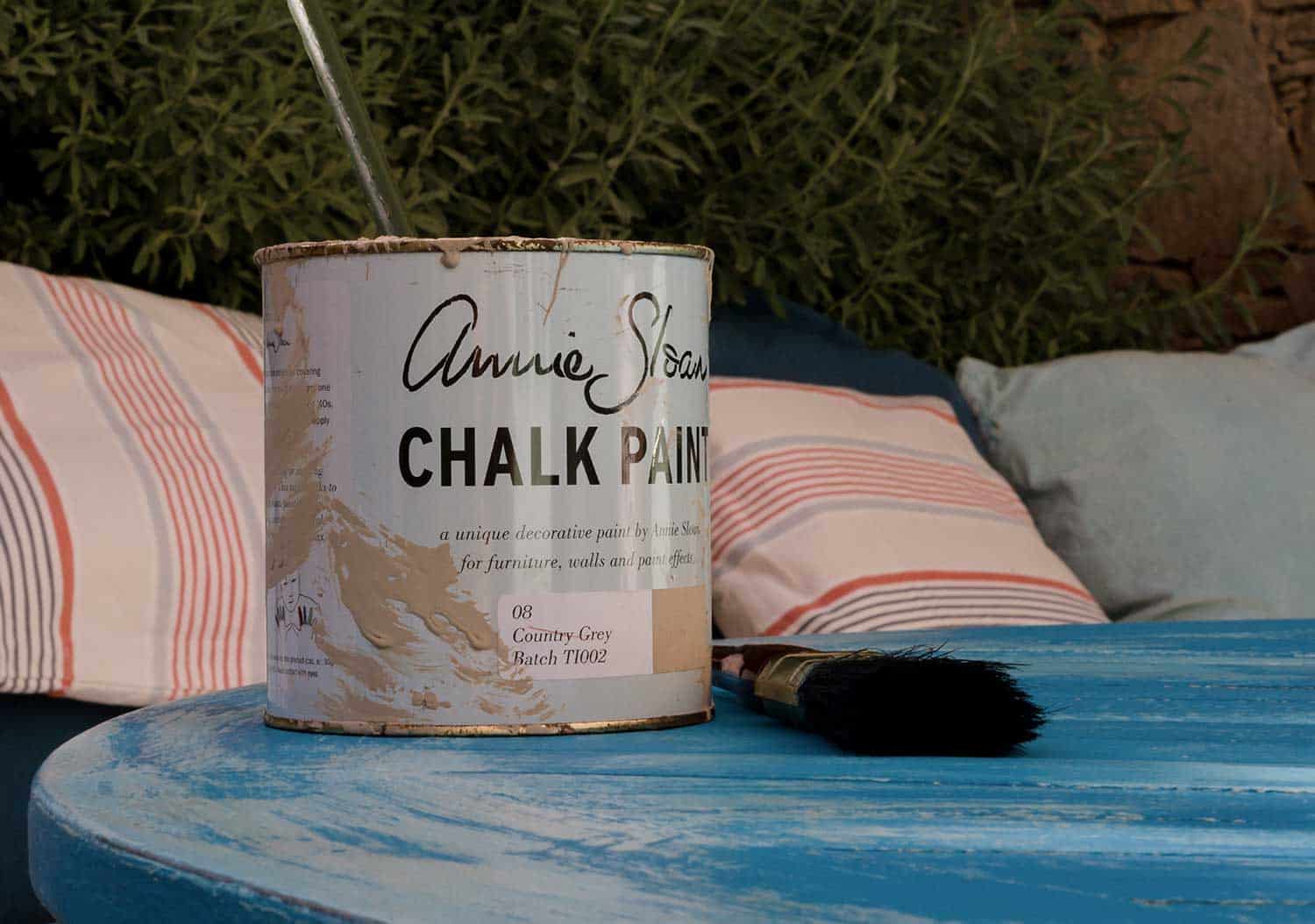 A tin of country chalk paint on the vintage table next to the paintbrush