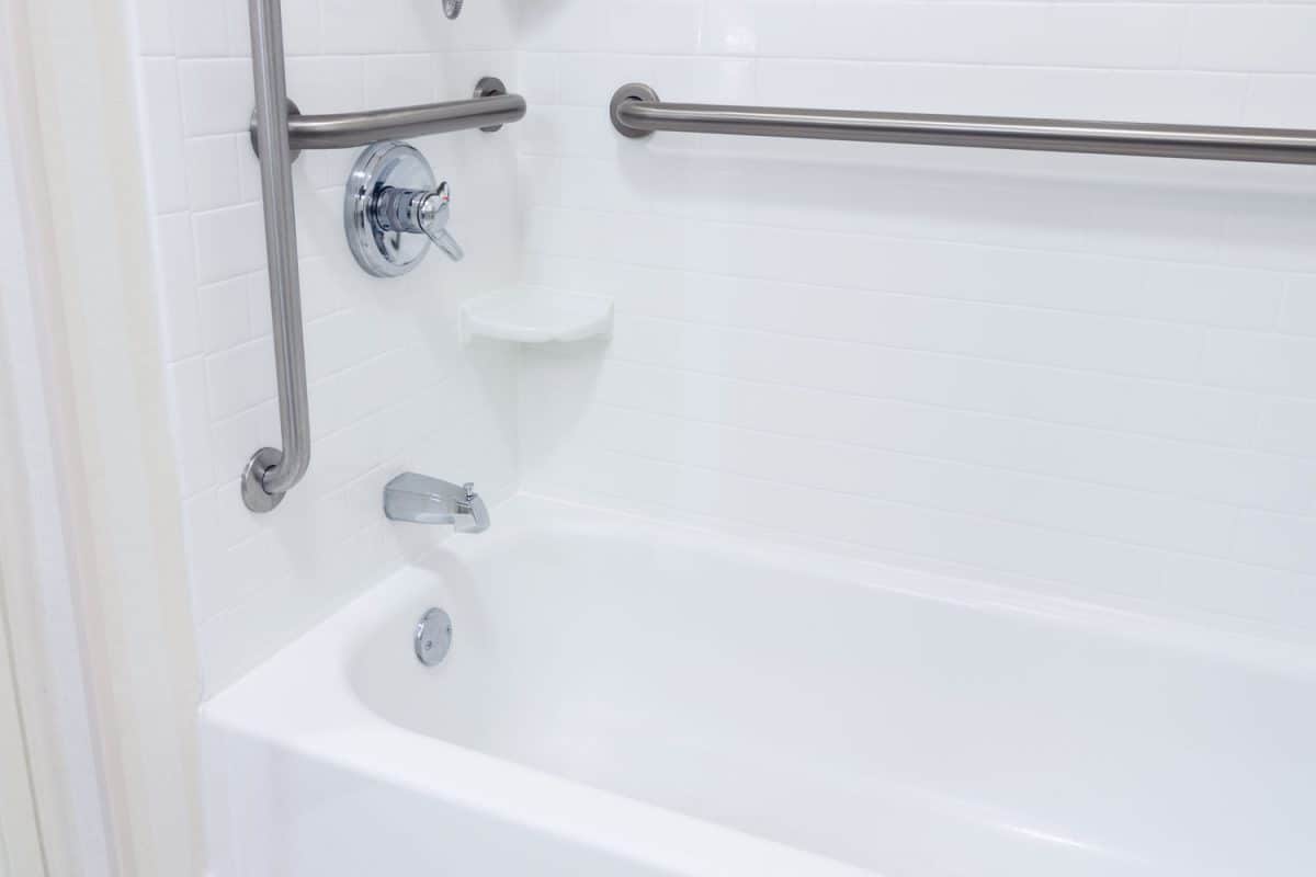 A white colored bathtub with assistive handles