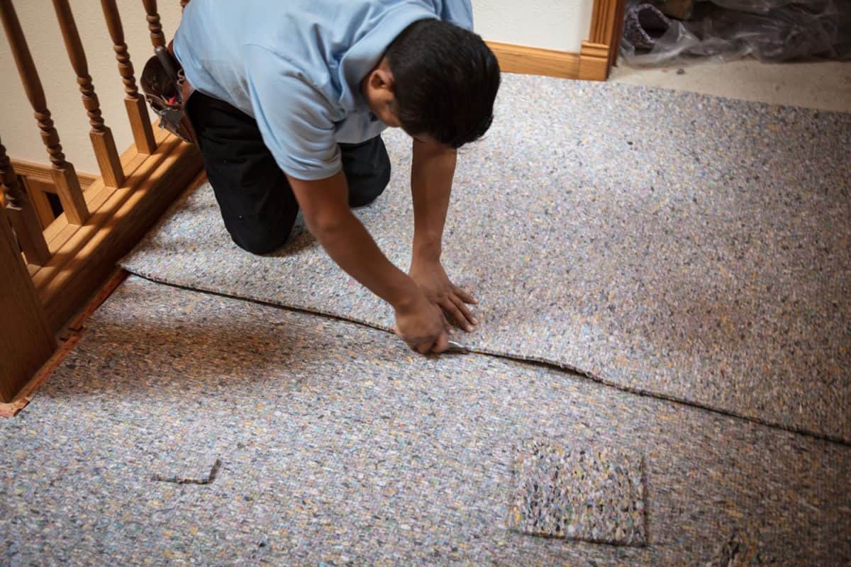 A worker installing carpet padding in the second floor