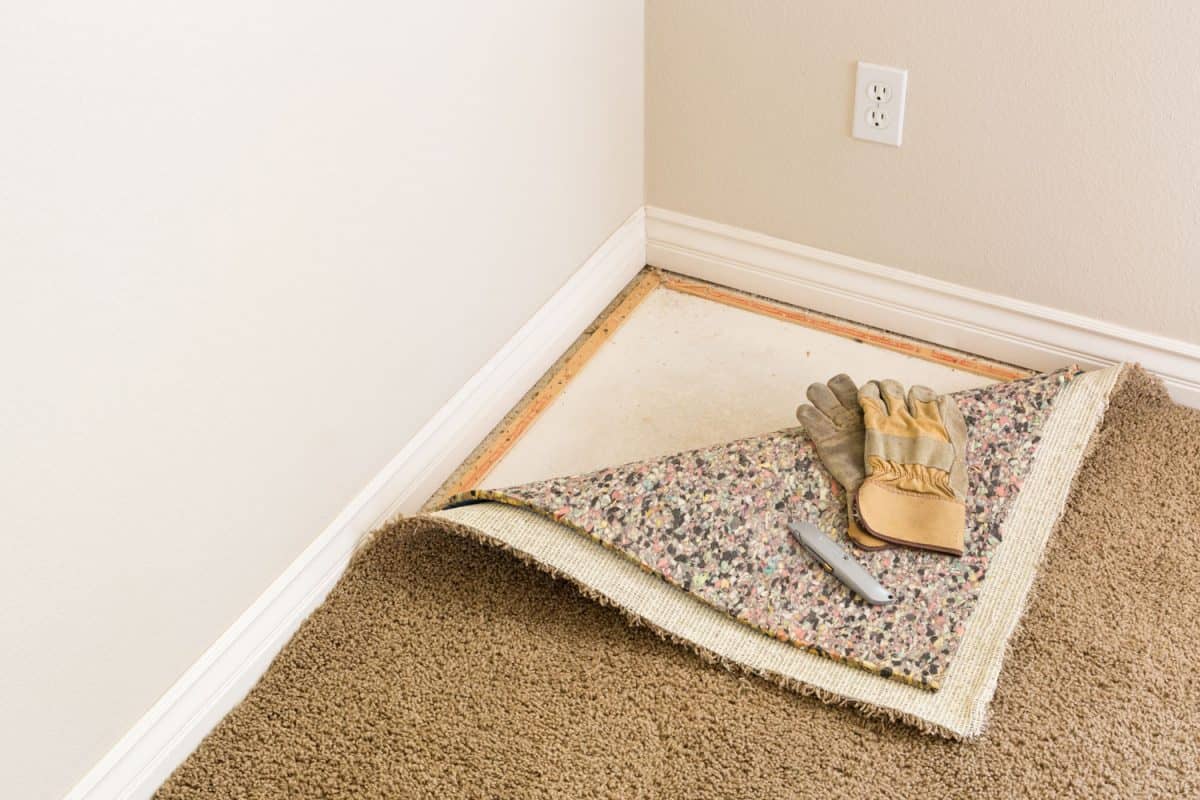 Construction Gloves and Utility Knife On Pulled Back Carpet and Pad In Room