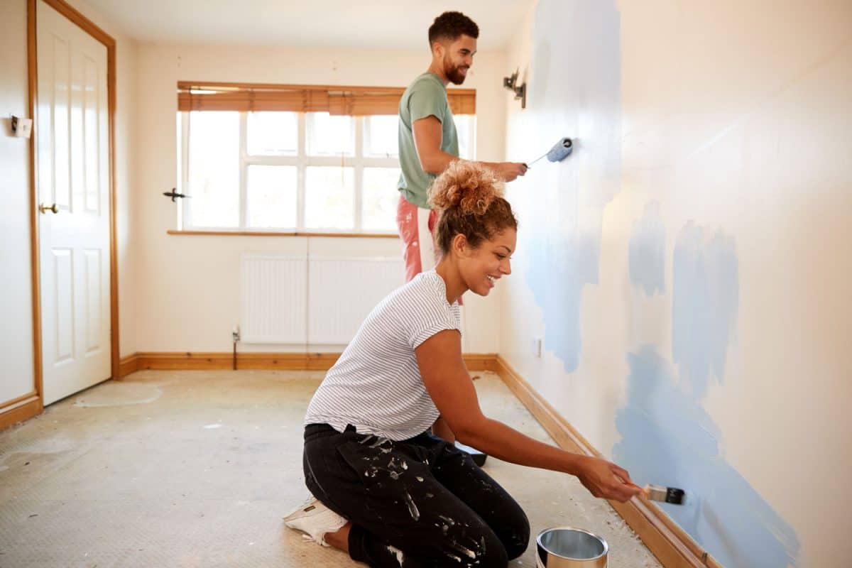 Couple Decorating Room In New Home Painting Wall Together