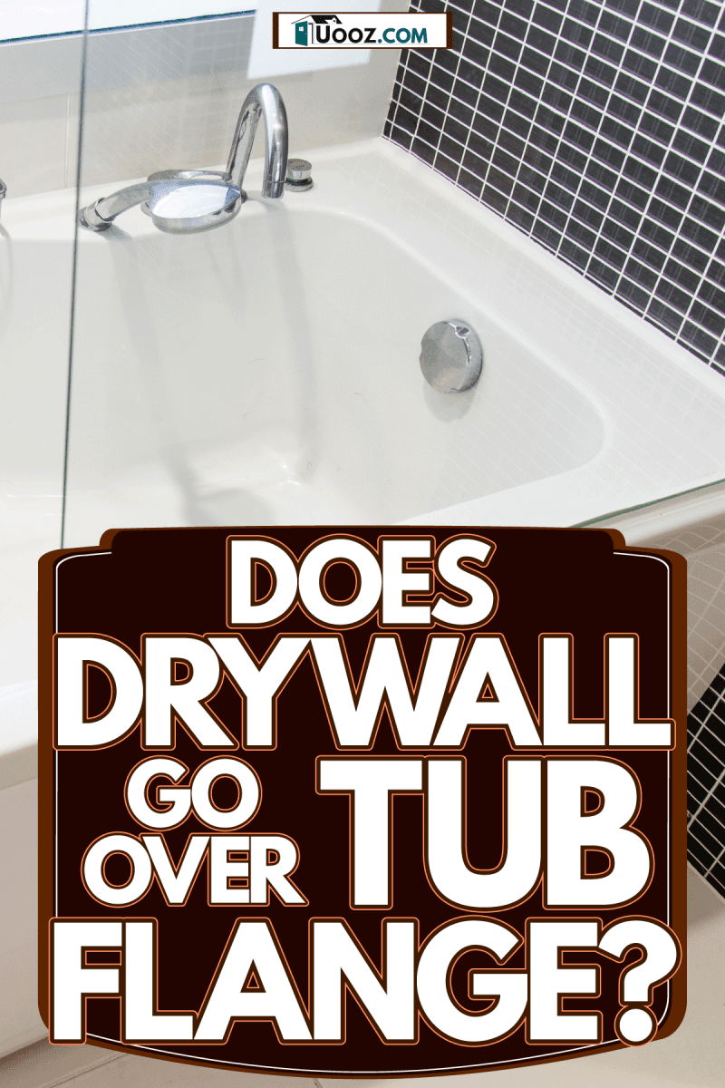 A white ceramic bathtub with a small tiled backsplash and a glass wall, Does Drywall Go Over Tub Flange?