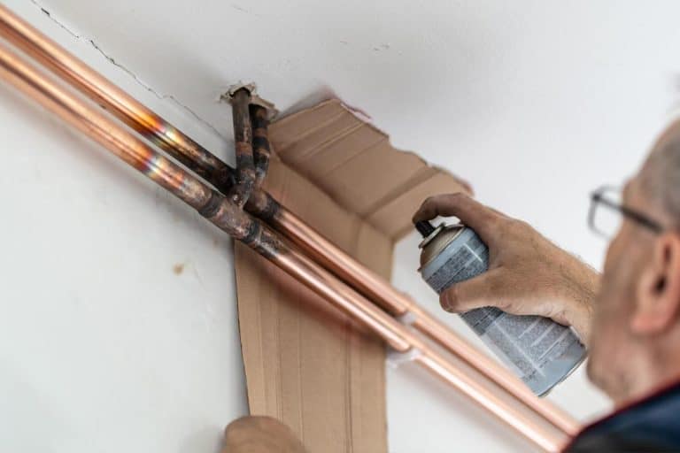 Man painting central heating pipes on the wall, Should You Paint Copper Pipes [And How To]