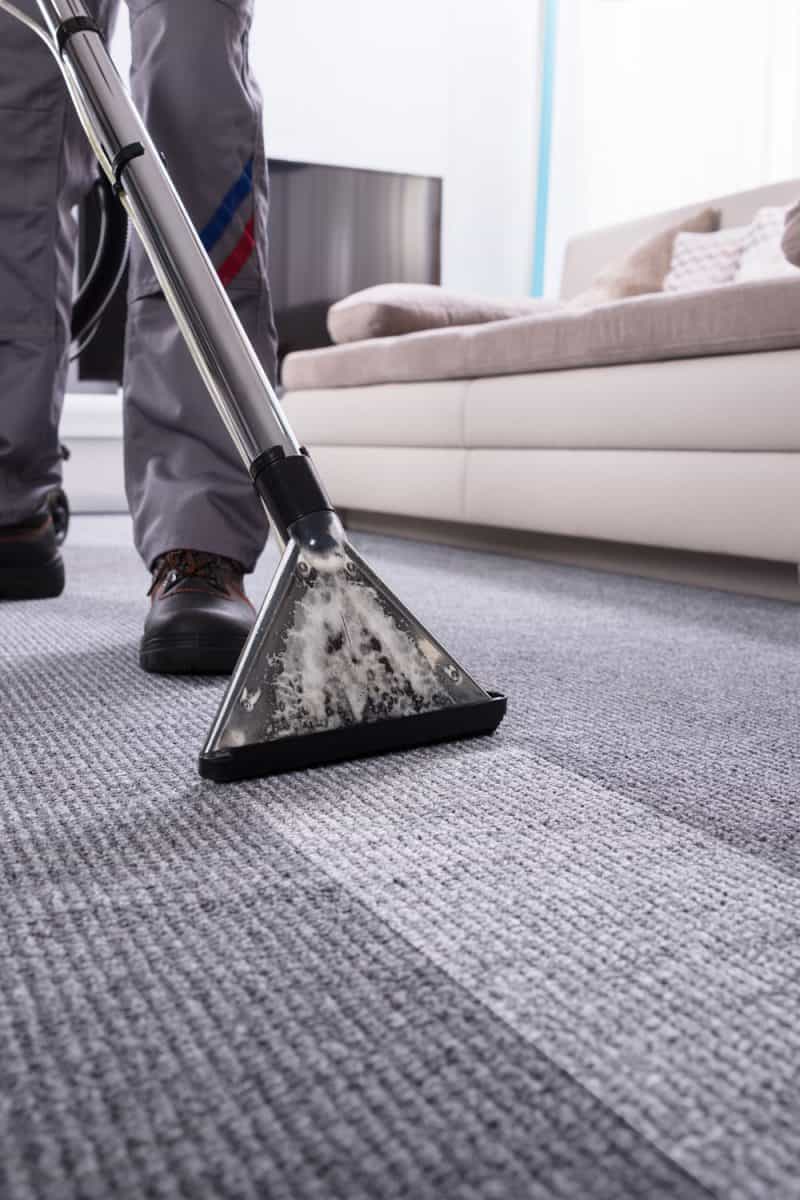 Man using a vacuum to clean the carpet