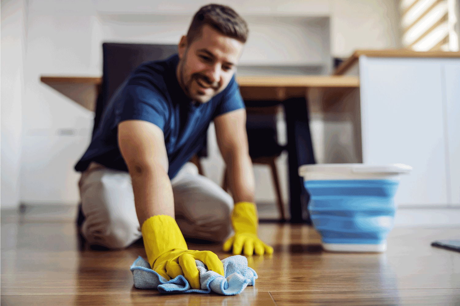 Man waxing parquet at home. Selective focus on hand with cloth. Rubber gloves on hands