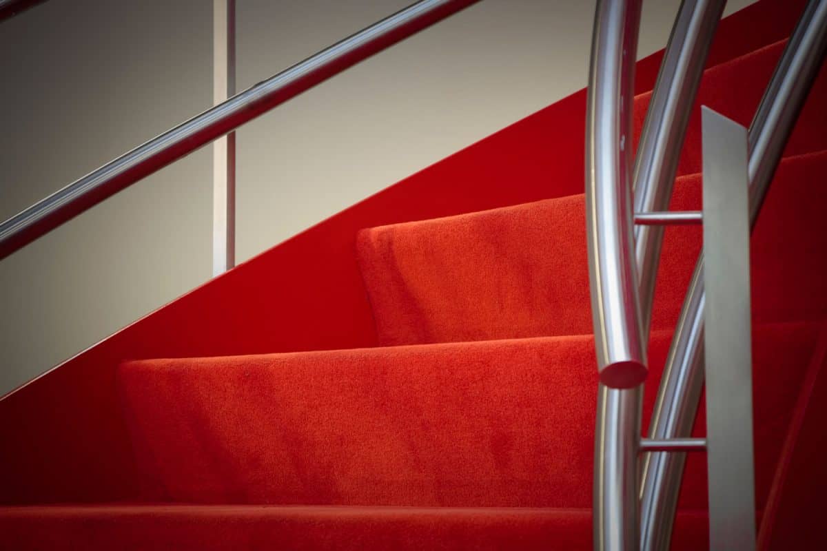 Red carpeted stairs of spiral staircase with steel handrails