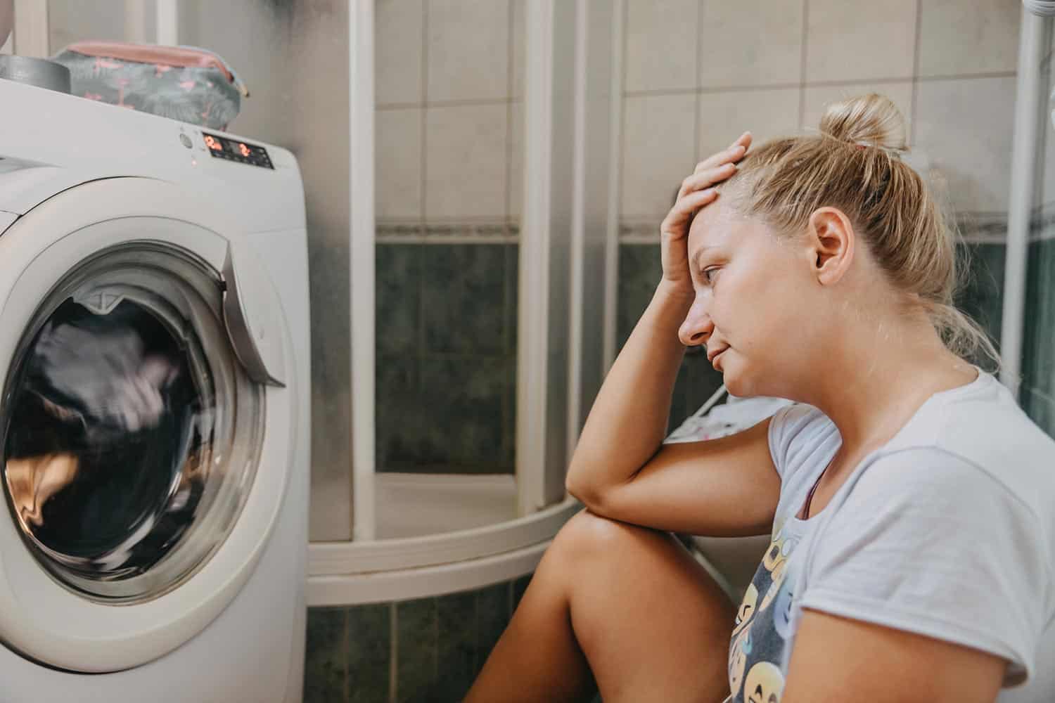 Upset woman sitting in laundry room