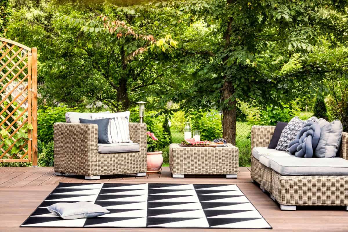 Wicker chairs outside the wooden deck patio with a black and white outdoor carpet