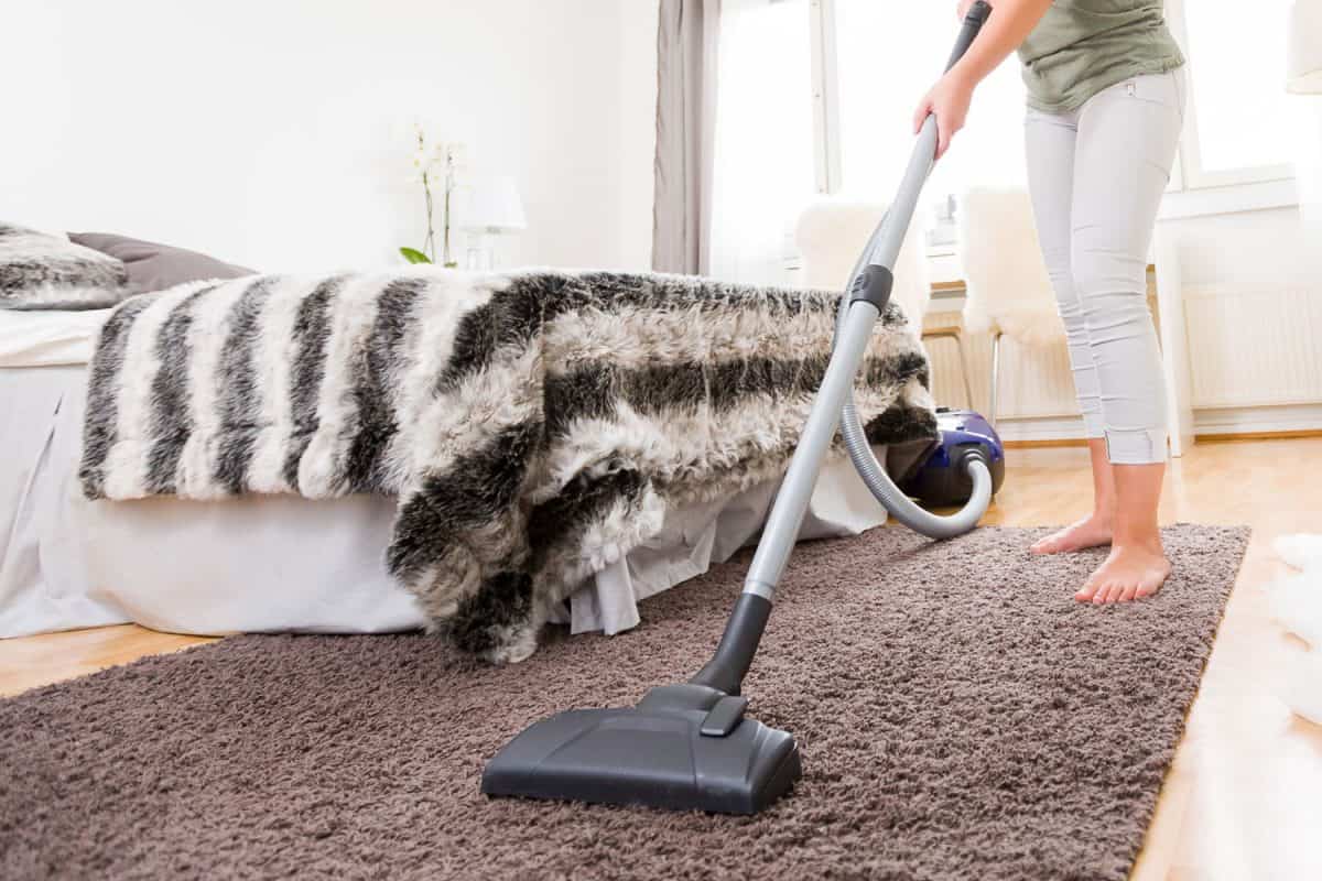 Woman cleaning her carpet using a vacuum