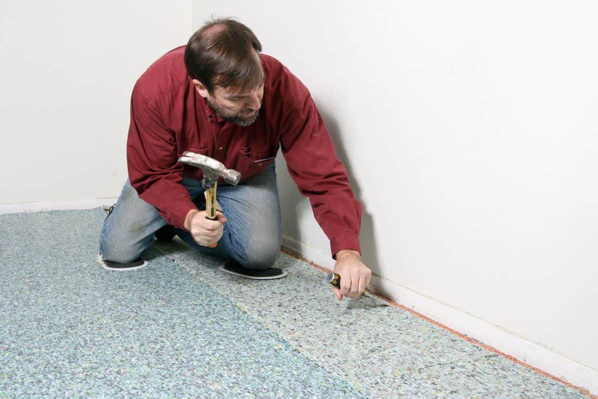 Worker using a hammer and chisel in installing the carpet padding