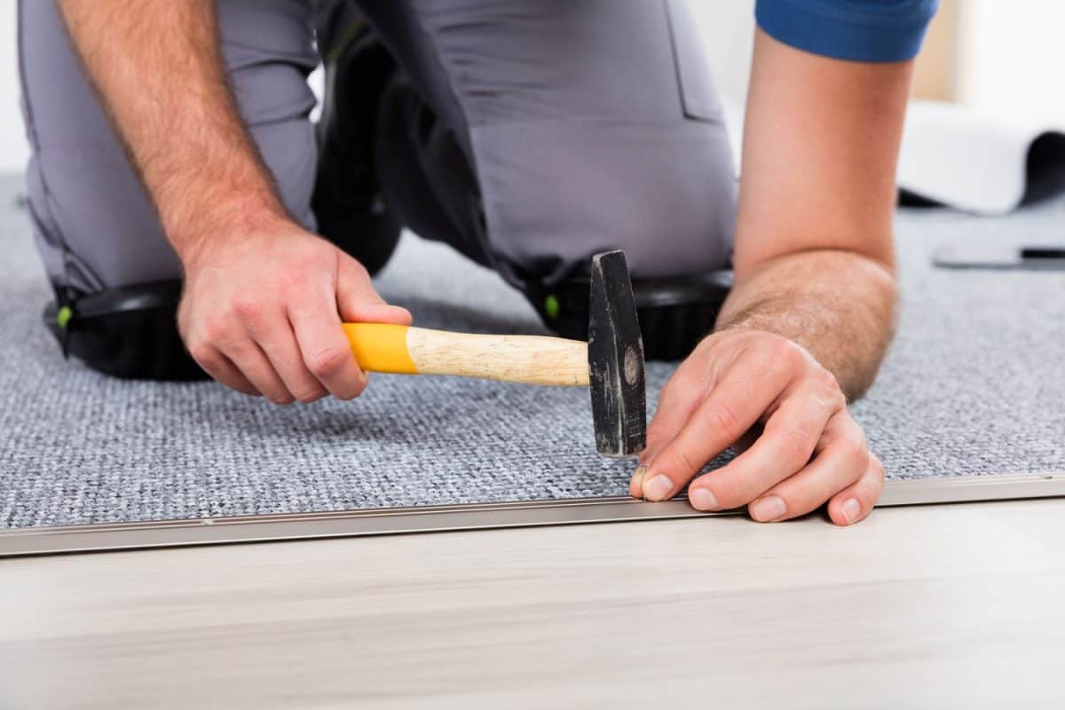 Worker using a hammer to install carpet padding