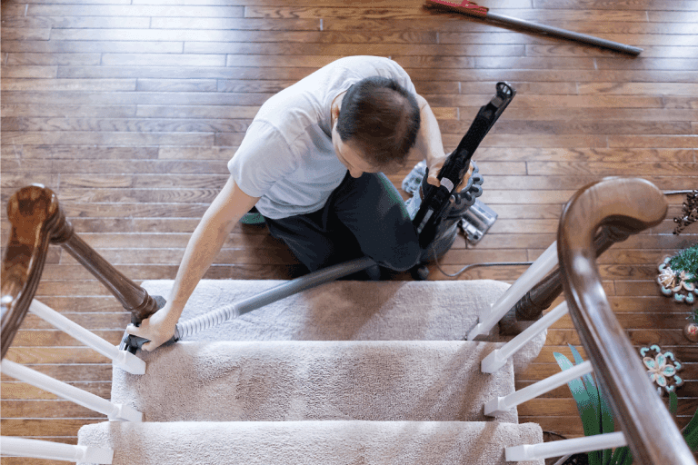 Young-man-house-husband-stay-at-home-dad-vacuumingon-carpeted-staircase.-How-To-Clean-Carpeted-Stairs