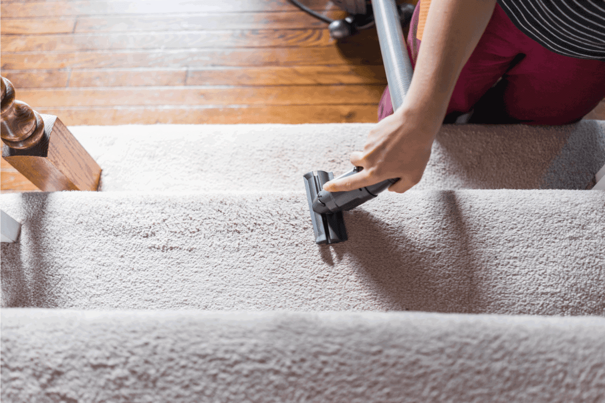 Young woman hand closeup flat top view looking down vacuuming using vacuum on carpet floor