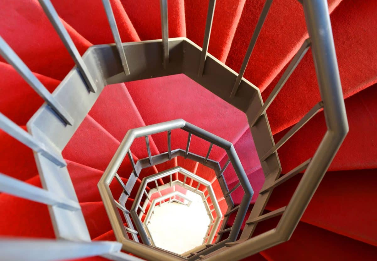 long iron spiral staircase with red carpet in a modern building