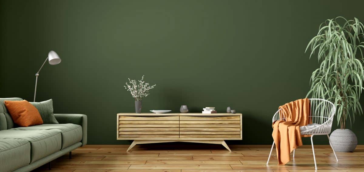 A green themed living room with green painted walls matched with a green sectional sofa and wooden accent chest