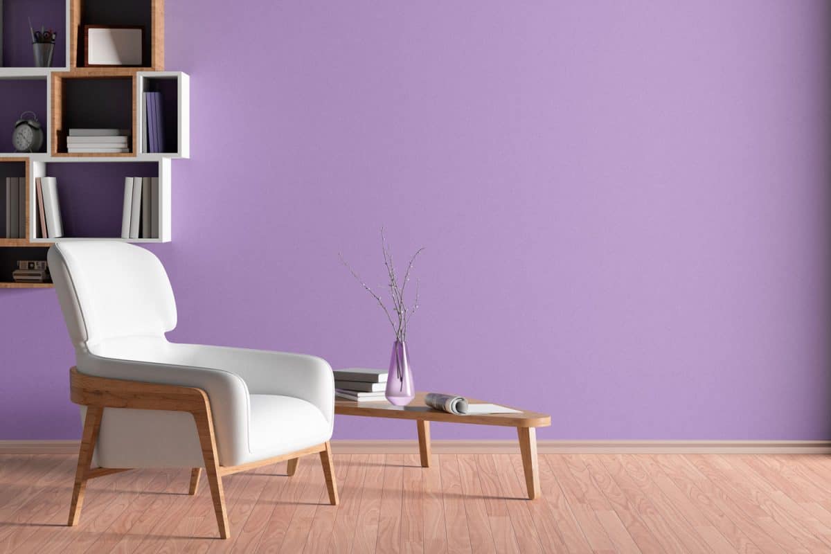 A purple colored living room wall matched with laminated flooring and a white armchair