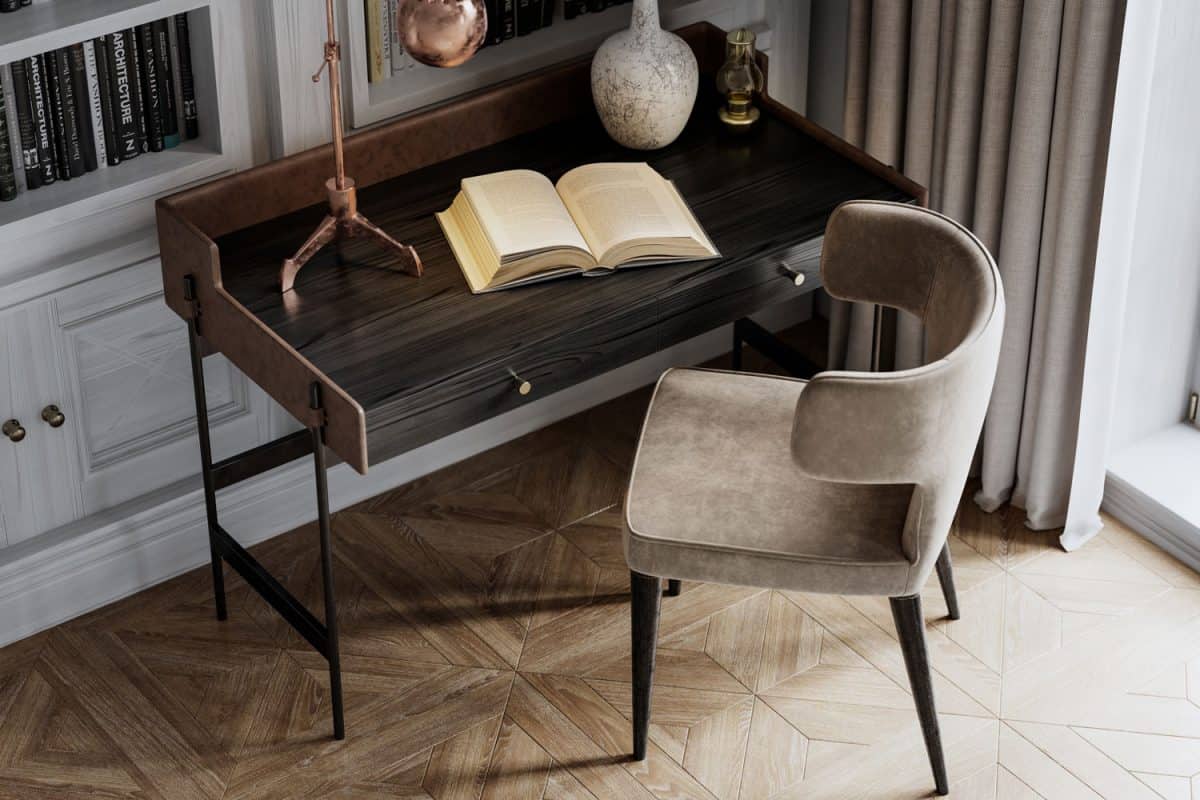 A small study table with patterned hardwood flooring, accent chairs and books on the shelves