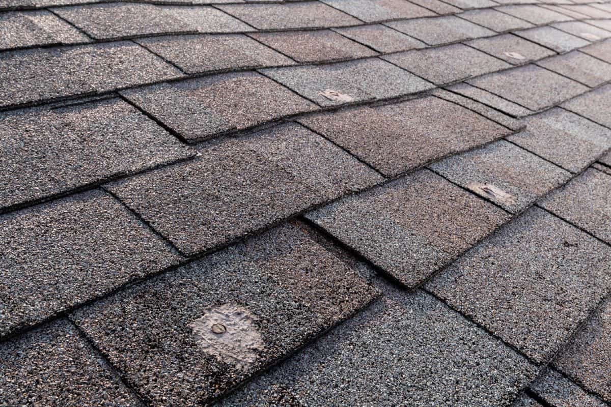 A wide view of a bad patches on a residential roof with architectural asphalt shingle