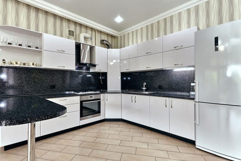 Interior of a luxurious and contemporary inspired kitchen with white panel boards and cabinets, Blue and white paint with a brush on the floor