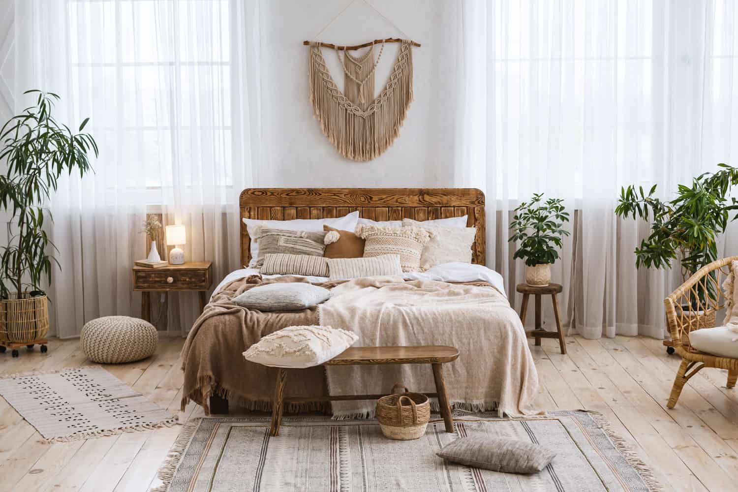 Modern interior of a bohemian themed bedroom with macramé accessories and wooden flooring