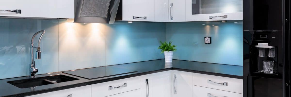 Modern kitchen with blue backsplash, black countertop and white cupboards and cabinets