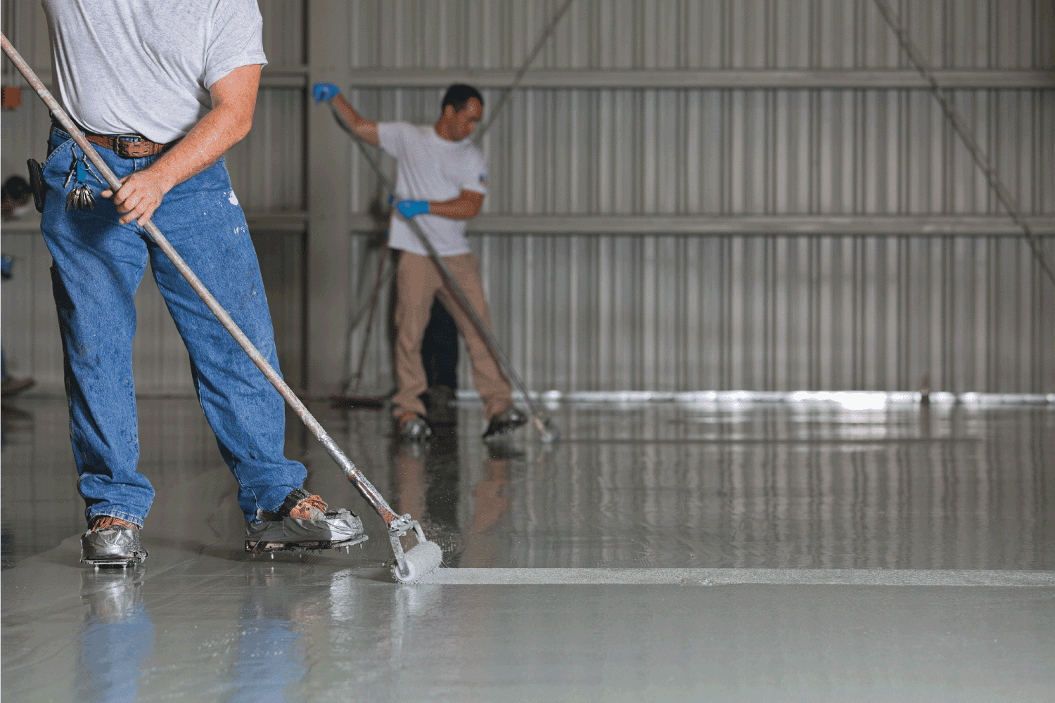 Painters apply epoxy paint to a warehouse floor.