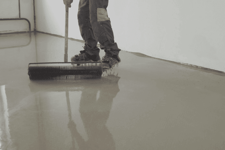 The-master-levels-the-epoxy-with-a-needle-trowel.-The-process-of-laying-the-self-leveling-epoxy.-Can-Epoxy-Floor-Go-Over-Tiles
