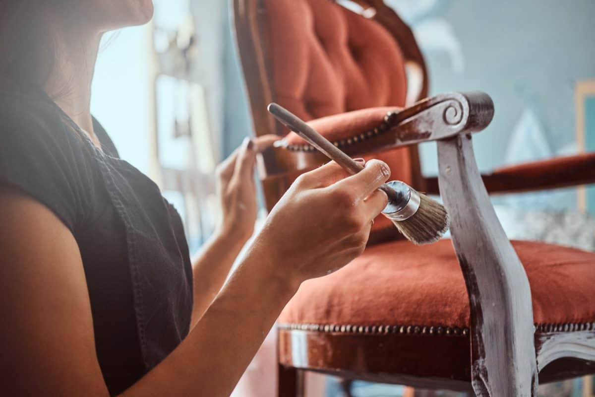 Woman using a paint brush to color the armchair