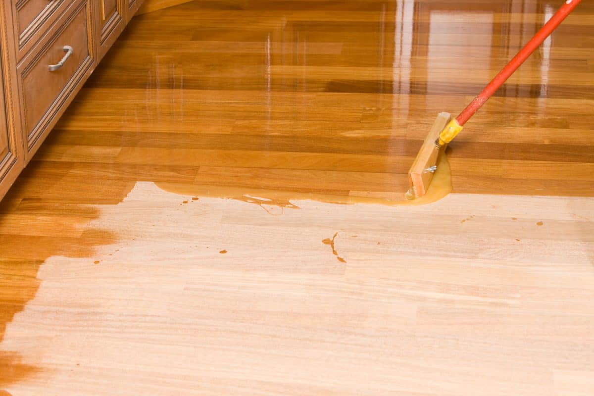 Worker using a flat tip mop in spreading polyurethane on the floor