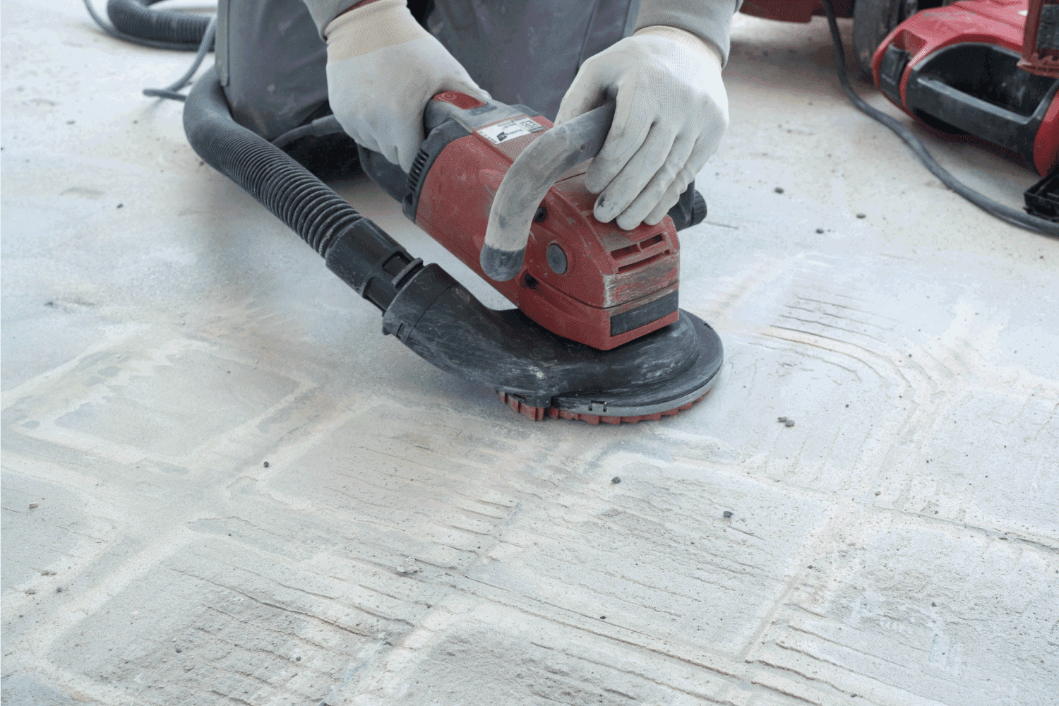construction worker uses a power concrete grinder for removing tile glue and resin during renovation work