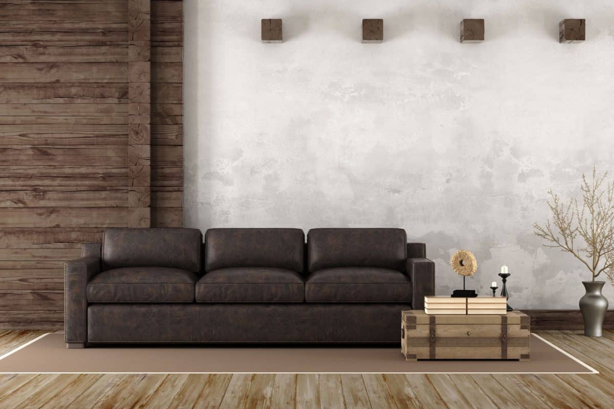 A dark brown leather sofa inside a modern house with wooden flooring and a coffee table