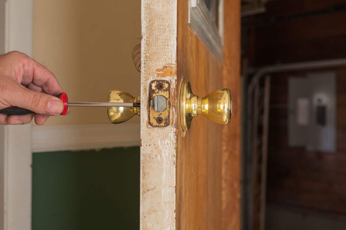 Door installer adjusting the screws on the doorknob