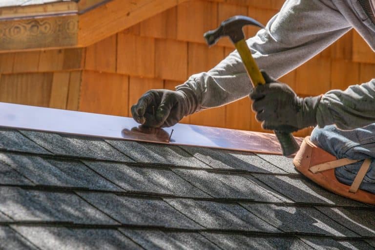 A man installing asphalt roof, How Far Apart Should Roofing Nails Be?