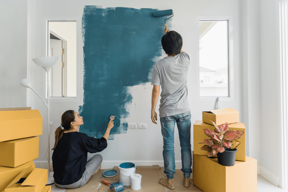 A couple painting their living room with a blue color