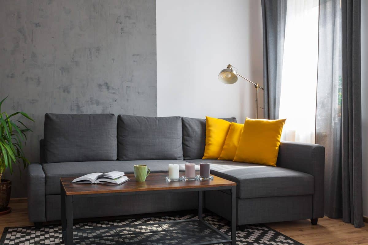 A gorgeous gray sofa with yellow throw pillows and a coffee table to match the gray living area theme