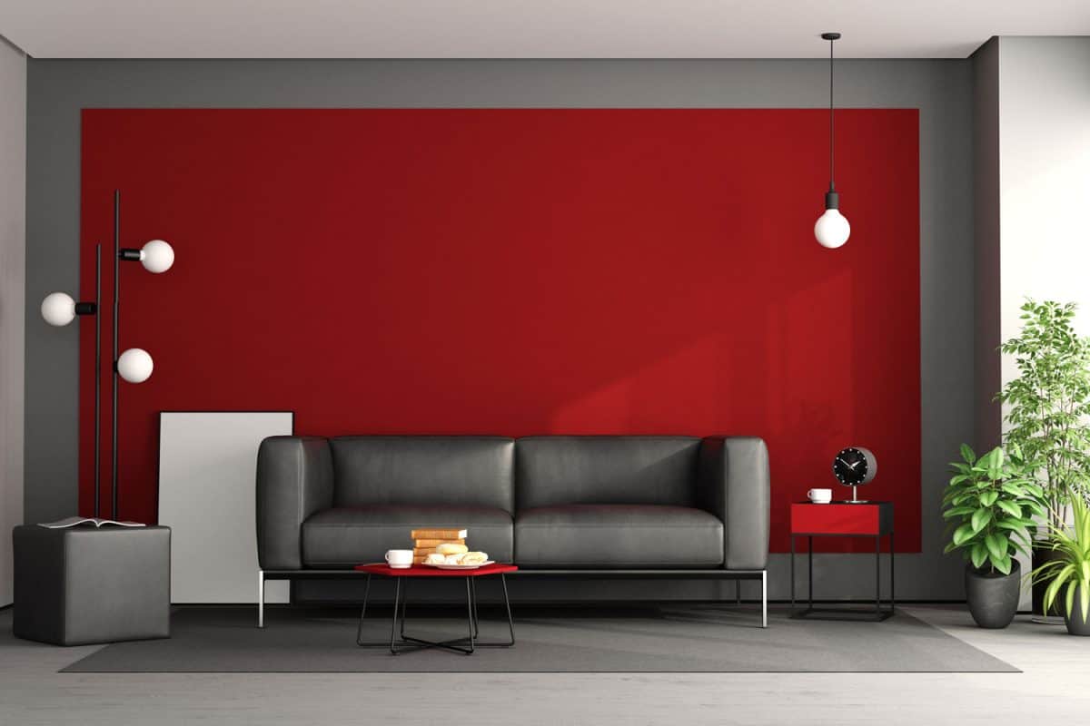 A gray sofa matching the red accent wall added with lamps on the corners