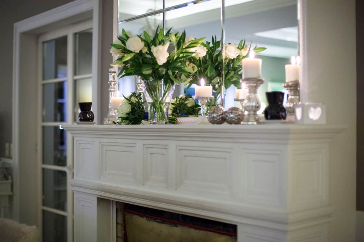 Flowers and candles placed on top of the fireplace mantel