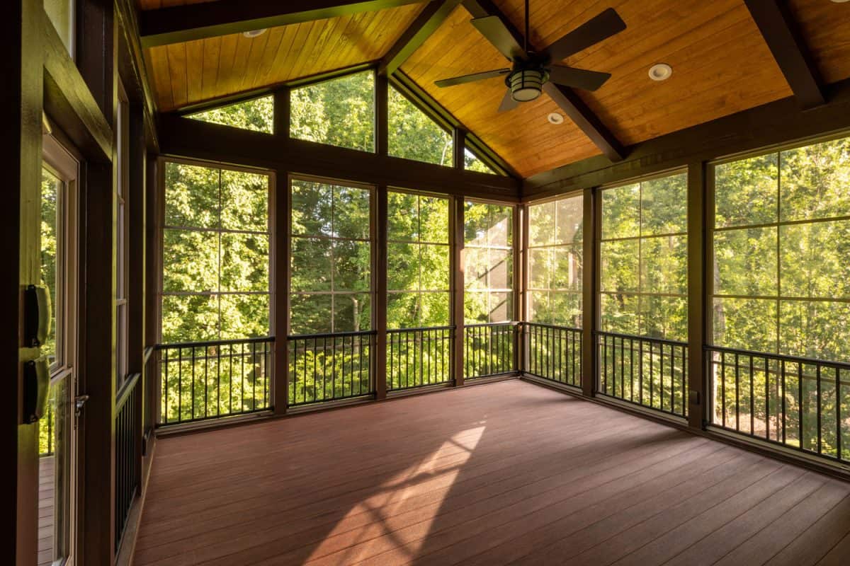 Interior of an empty porch with wooden flooring, glass walls, and wooden ceiling